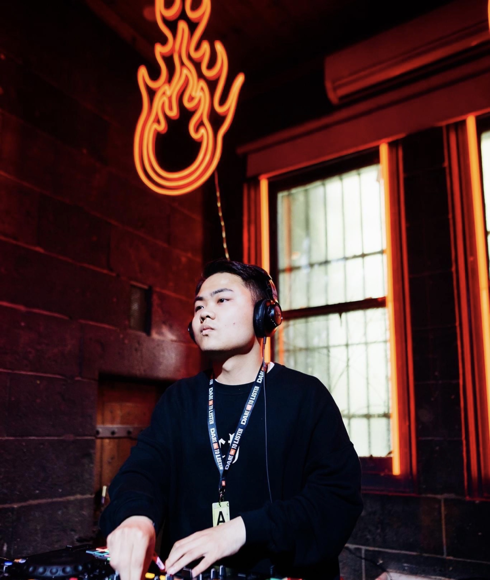 Bronx Wang wearing headphones during a DJ set under red neon light